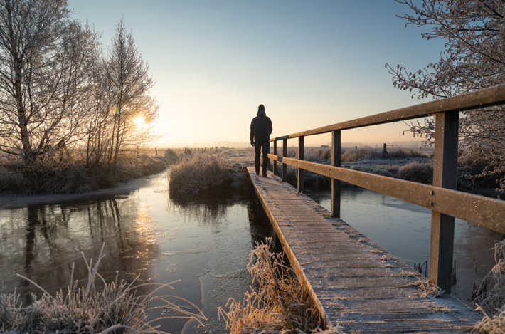 Человек стоит на замёрзшем мосту